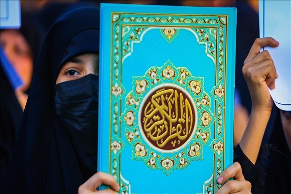 Muslim woman holding a copy of Quran in hands