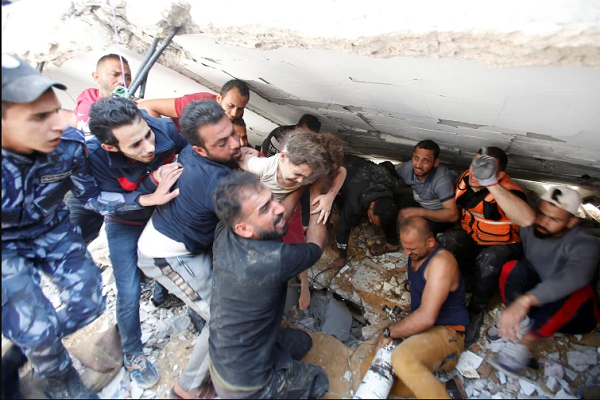 People rescue a child from under the rubble after an Israeli attack on Gaza.