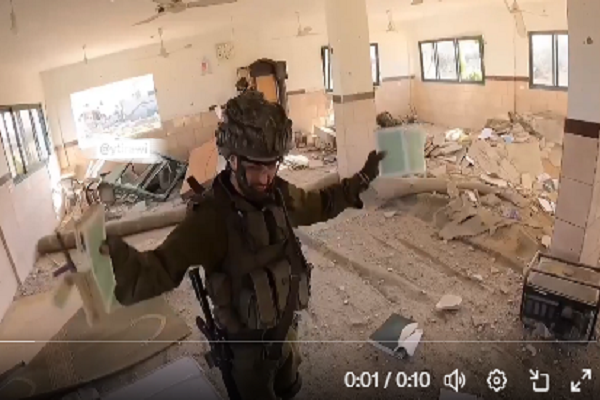 An Israeli soldier desecrating the Quran in a destroyed mosque in the Gaza Strip