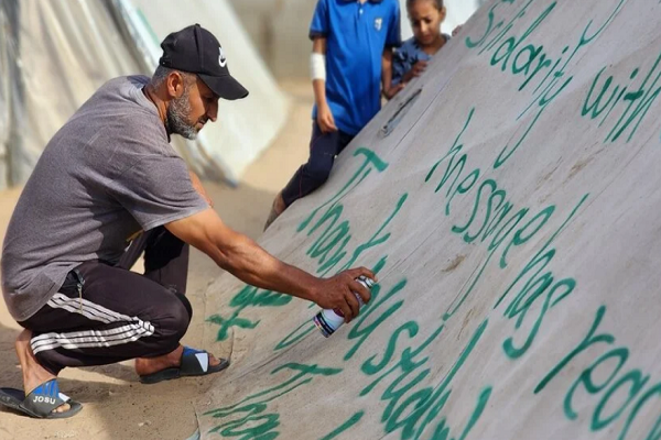 Palestinian man spray painting message of appreciation for American university students