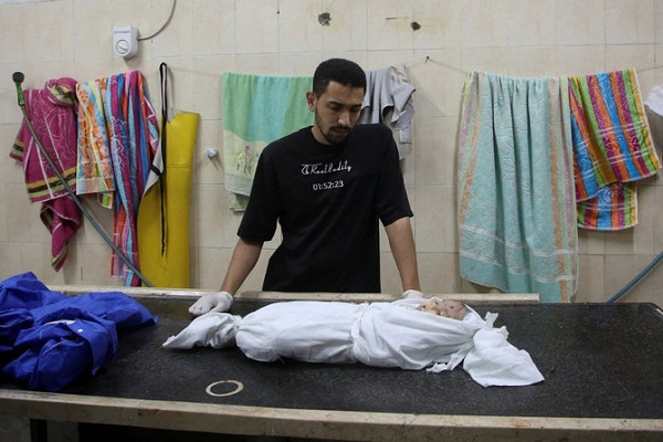 A Palestinian man watches over the body of a child who was killed in Israeli strikes in Rafah, southern Gaza Strip, on April 27, 2024