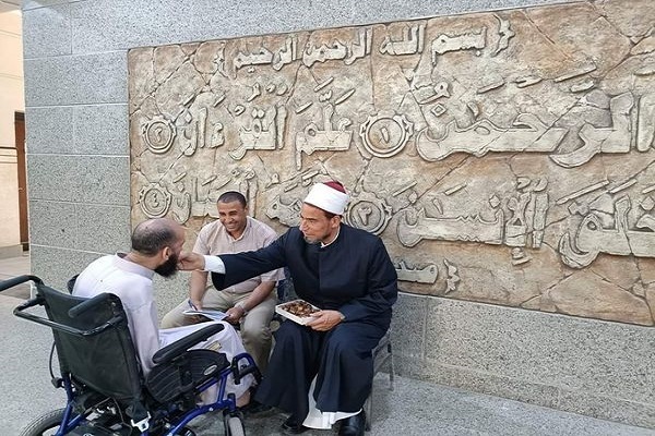 Abdul Fattah Khizr, the dean of Al-Azhar University’s Faculty of Quran and Quranic Sciences, helps a disabled student