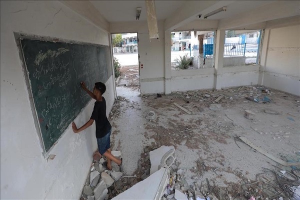A student writes on the blackboard in a classroom destroyed in Israeli attacks on Gaza
