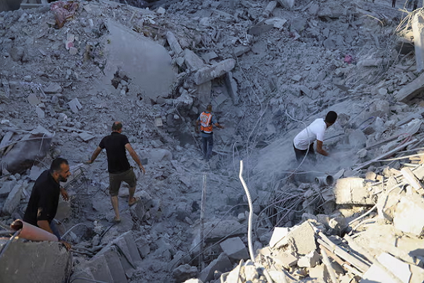 Palestinians search for bodies and survivors in the rubble of a building destroyed in an Israeli airstrike in Khan Younis, Gaza
