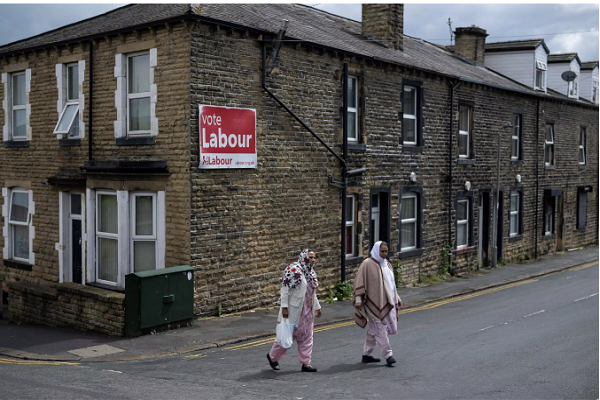 Two Muslim women walking past a UK Labour Party’s office