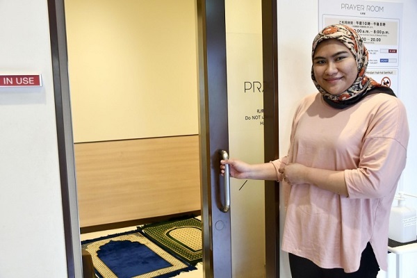 A visitor from Malaysia poses for a photo in front of the prayer room at the Matsuya Ginza department store in Tokyo.
