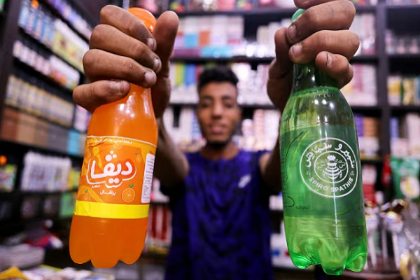 An Egyptian supermarket owner shows bottles of Egypt's local beverage brands Spiro Spathis and Diva Masr at his store, in Cairo on Sept. 1. Local brands are seeing a boost in sales amid boycotts of brands associated with the US, such as Coke and Pepsi.