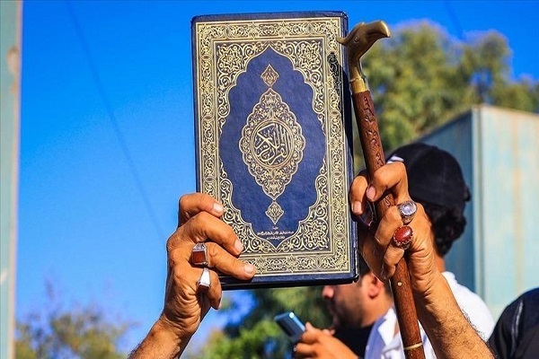 A man holds up a copy of the Quran during a demonstration against Quran desecration