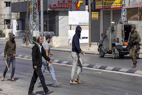 Illegal Israeli settlers attacking Palestinians under Israeli forces’ protection.