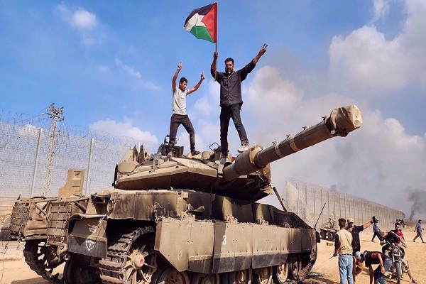 Members of Hamas's armed wing hold a Palestinian flag atop an Israeli tank in Gaza City on October 7, 2023.