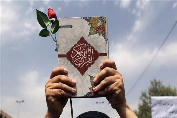 A demonstrator holds a copy of the Quran in a rally held against Quran desecration.