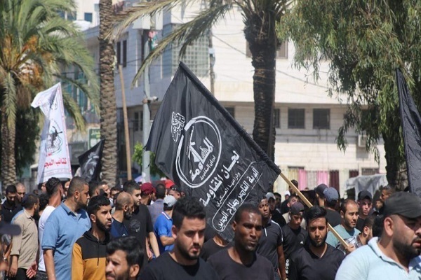 Demonstrators carrying a flag of the Popular Resistance Committees (PRC), a coalition of Palestinian groups