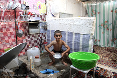 استحمام یکی از کودکان خانواده های مستاجر زلزله زده در محله زعفران سرپل ذهاب که بلاتکلیف در کانکس زندگی می کنند