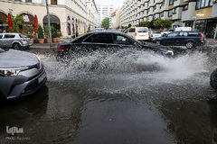یک خودرو پس از طوفان تابستانی در برلین، آلمان، از یک خیابان سیل زده عبور می‌کند. پس از سه روز تجربه دمای 30 درجه سلسیوس، پایتخت آلمان شاهد رعد و برق شدید بود. 