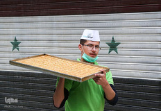 یک مرد در حال حمل شیرینی‌‌های محبوب ماه رمضان در شهر دمشق سوریه